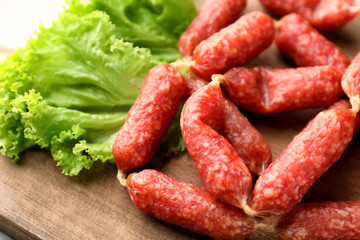 Delicious smoked sausages on wooden board, closeup