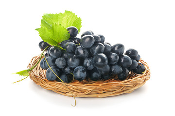 Wicker plate with ripe sweet grapes on white background