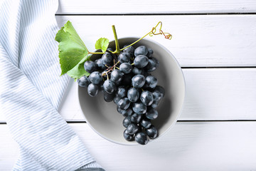 Plate with ripe sweet grapes on white wooden background