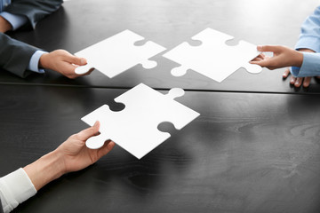 Business team with pieces of puzzle on dark table