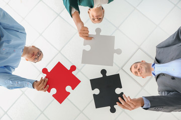 Business team with pieces of puzzle in office, bottom view