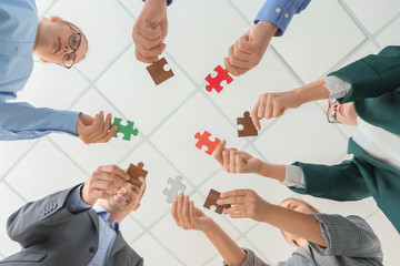 Business team with pieces of puzzle in office, bottom view