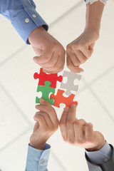 Business team with pieces of puzzle in office, bottom view - obrazy, fototapety, plakaty