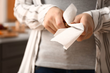 Woman wiping knife with paper towel in kitchen, closeup