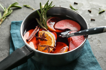 Saucepan of delicious mulled wine on grey table