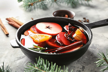 Saucepan of delicious mulled wine on grey table