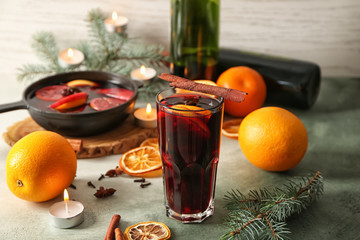 Glass of delicious mulled wine on color table