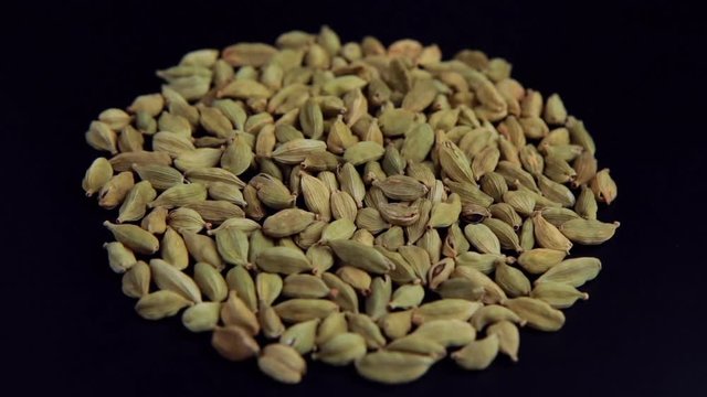 Green cardamom seeds rotating in slow motion top view