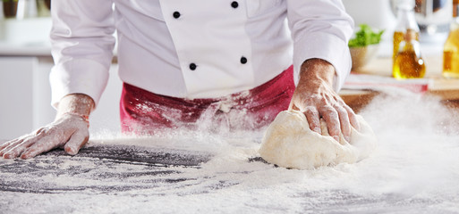 Man sliding dough along table to pick up flour - obrazy, fototapety, plakaty