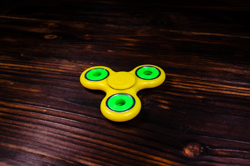 Yellow fidget spinner on wooden desk