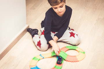 Small boy playing with car toy on the floor.