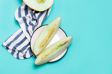 Minimum flat lay of fresh melons sliced on a pastel blue background with copy space