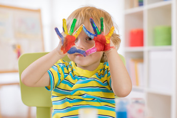 cute cheerful kid with hands painted in bright colors