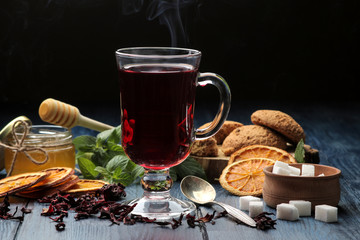 Hot red karkade tea with honey and biscuits. autumn. winter. on blue wooden table