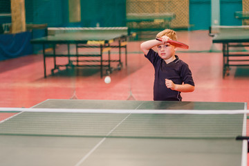 a boy playing table tennis in the tennis hall
