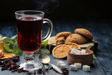 Hot red karkade tea with honey and biscuits. autumn. winter. on blue wooden table