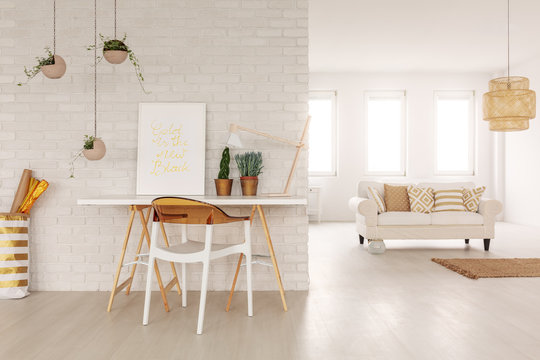 Open space living room interior in real photo with white sofa with cushions in the background, desk with poster and plants standing by the brick wall and plastic chair