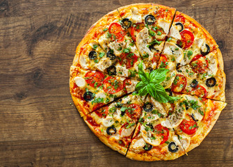 sliced Pizza with Chicken meat, Mozzarella cheese, tomato, olive. Italian pizza on wooden background