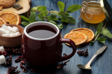 Hot red karkade tea with honey and mint. Autumn or winter soft drink. on blue wooden table