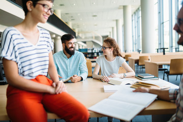 Young attractive students spending time in library