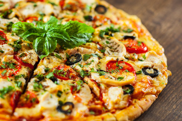 sliced Pizza with Chicken meat, Mozzarella cheese, tomato, olive. Italian pizza on wooden background