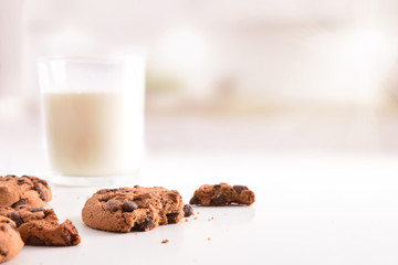 Biscuit with chocolate chips and glass of milk on table