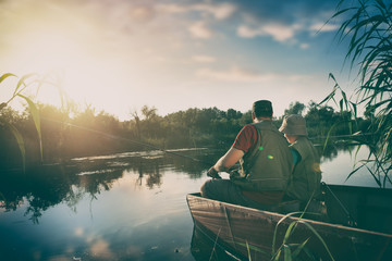 père et fils attrapent du poisson d& 39 un bateau au coucher du soleil