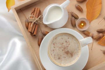 Autumn composition with hot coffee and yellow leaves on a tray on the bed. view from above