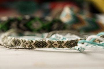 Handcrafted friendship bracelets on a white table with different colored threads