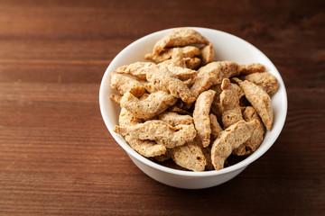 Raw dry soya meat chunks in a white bowl on a wooden table