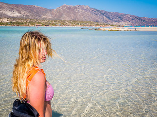 Beautiful blonde sexy curvy girl walking on the paradise beach of Elafonisi, Crete, Greece, close to the southwestern corner of the Mediterranean island of Crete, known for its pink sand beaches