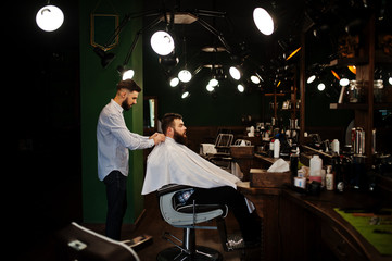 Handsome bearded man at the barbershop, barber at work.