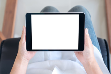 Top view mockup image of a woman holding black tablet pc with blank white screen while sitting on a chair
