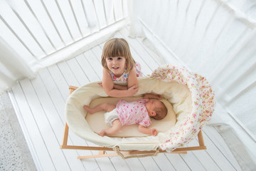 Smiling girl and newborn baby in cradle, top view