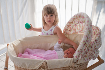 Happy toddler girl playing with her newborn sister © poplasen