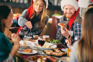 Friends having dinner at home at Christmas eve. Winter holidays concept.