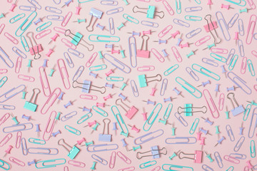 Colorful pastel background created with multiple office supplies like paper clips, binder clips and push pins.