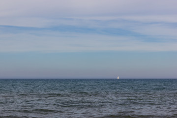 A white jacht boat on the horizon in the mediterranean sea