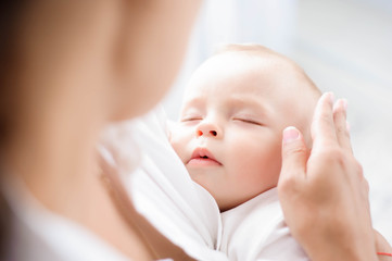 Baby sleeping on the mother's chest. Young mother cuddling baby - obrazy, fototapety, plakaty