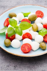 Delicious caprese salad with ripe cherry tomatoes and mini mozzarella cheese balls with fresh basil leaves.