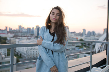 Obraz premium Attractive young woman stands against city and sunset.