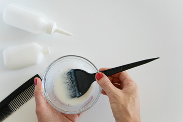 Top view of woman hand mixing hair dye color and dye hair products on white background, space for...