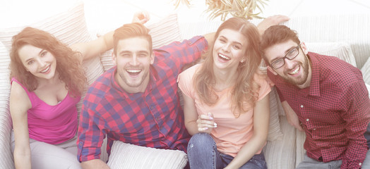 four happy friends laughing while sitting on the couch