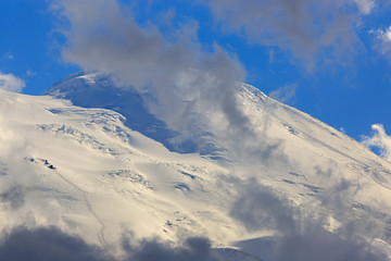 Fototapeta na wymiar Climbers trail on the eastern top of Mount Elbrus, the slope with snow is visible through the clouds. Mountain range in the North Caucasus in Russia.