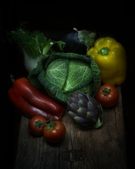 composizione di ortaggi misti su tavolo di legno e sfondo nero. peperone rosso e giallo, cavolo verza, finocchio, melanzana, pomodori rossi, carciofo