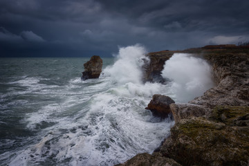 Dramatic nature background - big waves and dark rock in stormy sea, stormy weather. Dramatic scene. Contrasting colors.Beautiful natural landscape, seascape at Tyulenovo, Bulgaria. 
