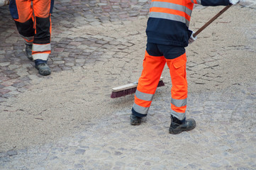 Fototapeta na wymiar retail of worker legs on cobblestone maintenance site on main place