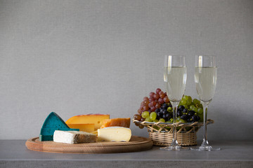 Cheese and grapes in wicker basket with white wine