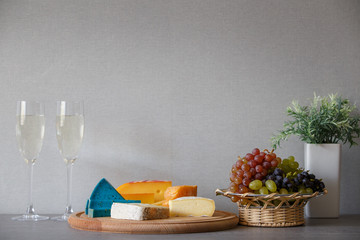 Cheese and grapes in wicker basket with white wine