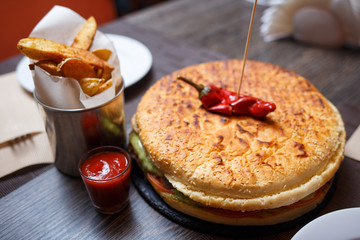 Golden potato wedges with big burger on the table